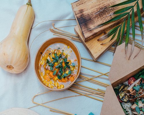 A table full of fresh vegetables, grains, and a bowl of soup